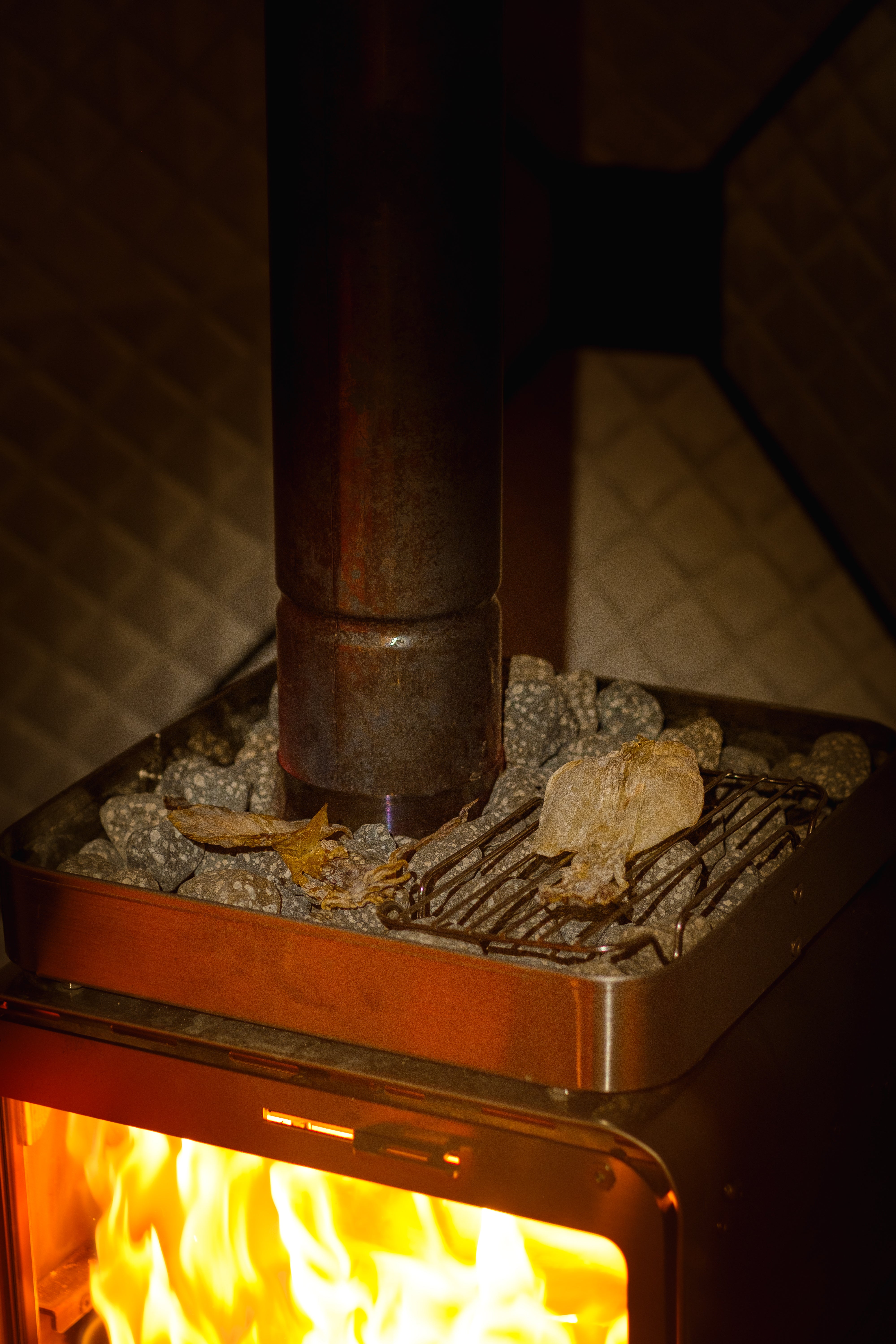 Sauna stones arranged in the CUBE STOVE Stone Basket around the rear-exhaust chimney